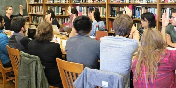 Student raise their hands in a small seminar