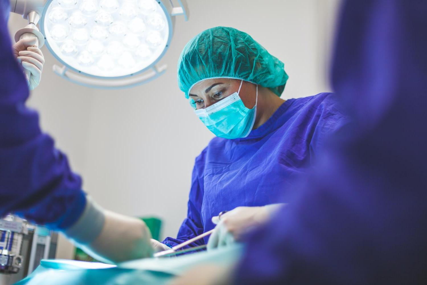 A surgeon conducts surgeon under the bright lights of an operating room