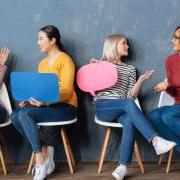 Four women holding paper conversation bubbles and talking