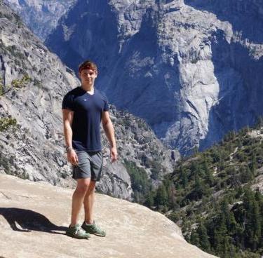 Lukas Buecherl stands on a rock in front of mountain scenery.