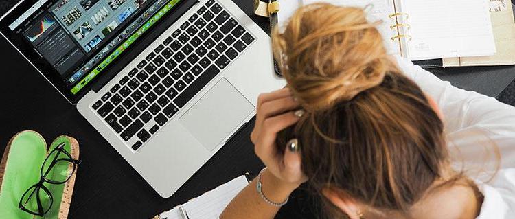 Woman with her head in her hand staring at a laptop