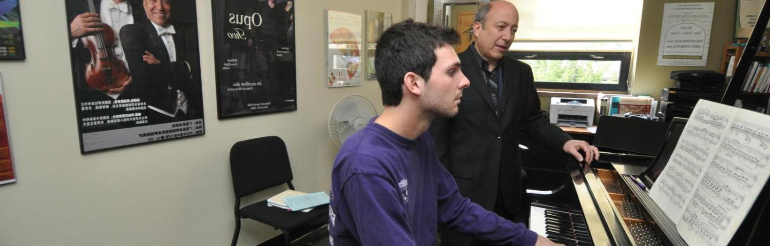 教师 member teaching a student who's playing the piano.