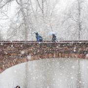 学生们在雪中走过大学池塘桥