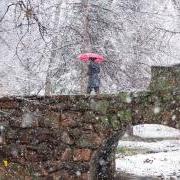 学生在雪中走过大学池塘桥