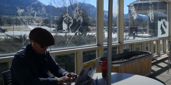 People work in the sunshine on tables on the front patio of the SEEC building, 后面是熨斗山