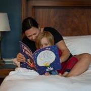 Caregiver and child sitting in bed reading bedtime story