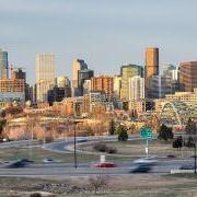 Denver's skyline. The foreground shows cars driving on a highway. 